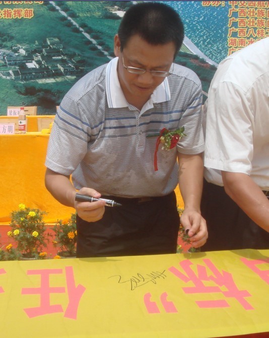 廣西新港灣公司副總經(jīng)理姚方明在“奮戰100天，如期實(shí)現魚(yú)梁工程截流、通航、發(fā)電‘三大目標’”橫幅上簽字